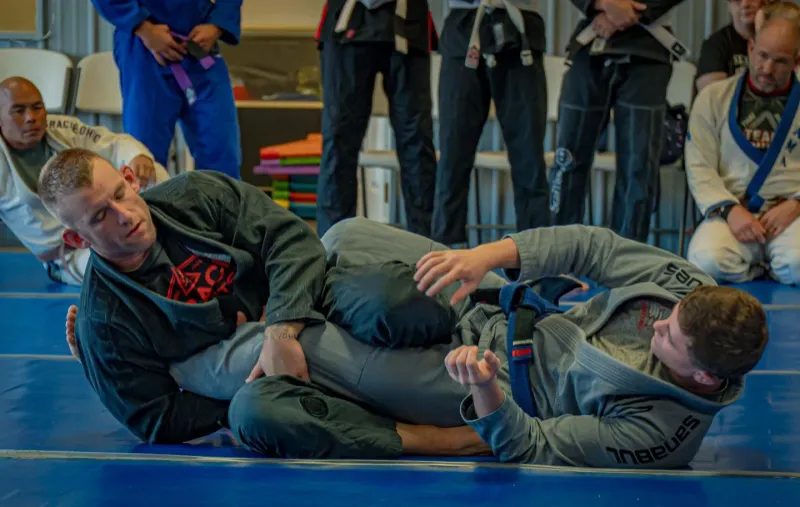 Students watching a coach break down a guard position during BJJ Fundamentals
