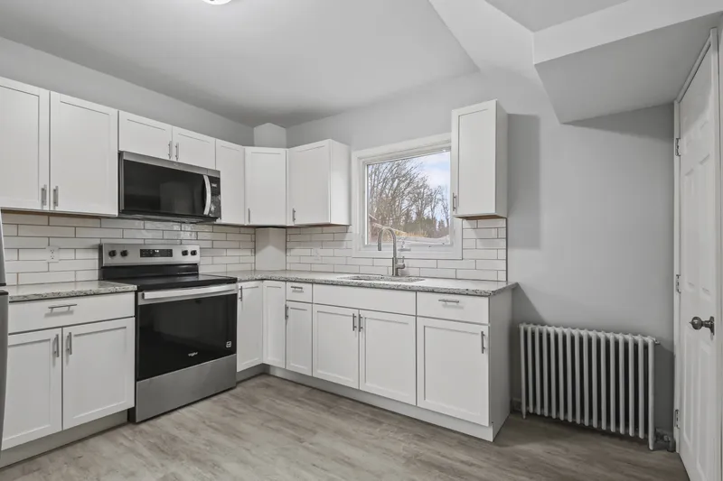 Kitchen after renovation, with white cabinets and new appliances