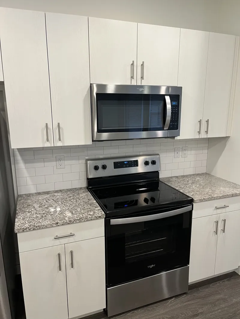 White shaker kitchen with stainless steel range and microwave