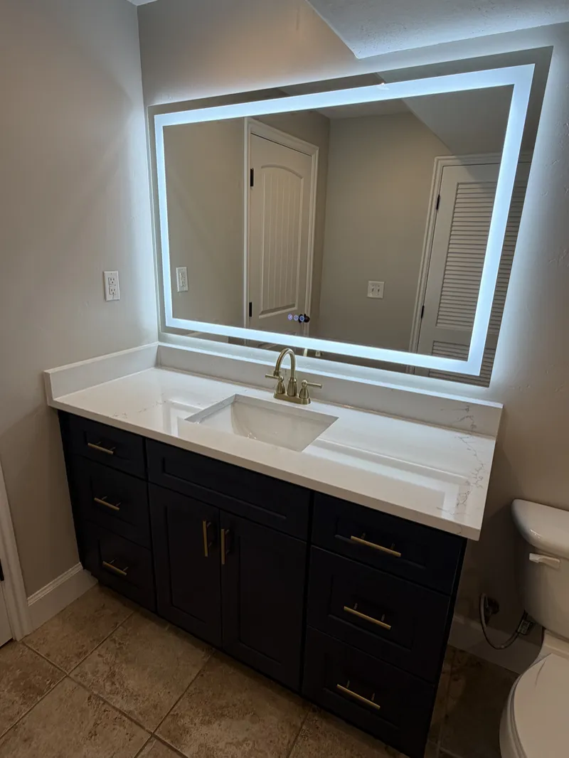 Navy vanity with brass hardware and backlit mirror
