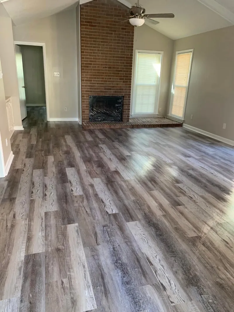 Brick fireplace and plank floors in a living room cleaned by Pretty in Pink Cleaning Service in Wetumpka, AL
