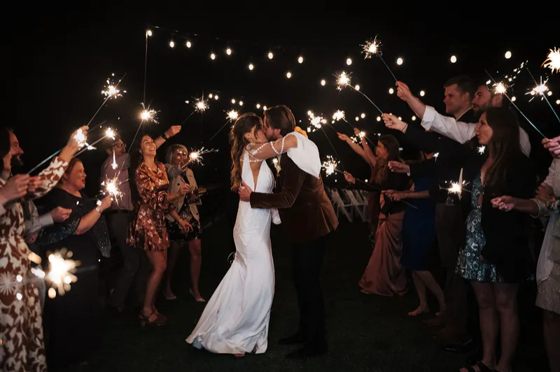 A couple celebrating their wedding send-off surrounded by sparklers