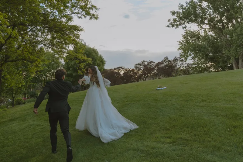 A newly married couple walking together across the Stone Crossing lawn