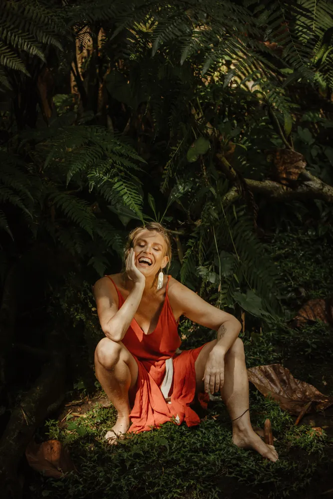 Olivka Wilk laughing, sitting among tree ferns.