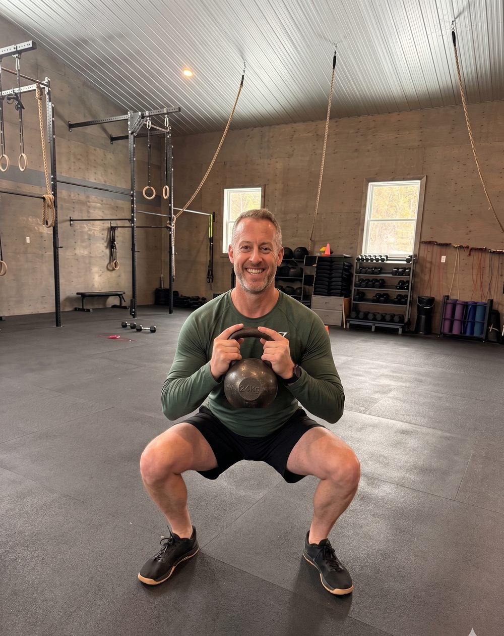 A BTB member holds the bottom of a goblet squat with a kettlebell