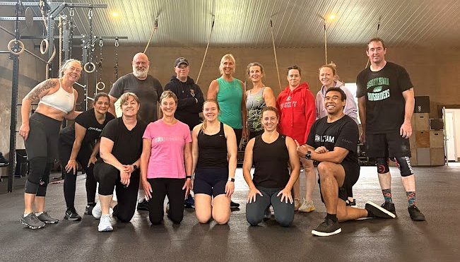 A full BTB class of adult members together on the training floor after a session