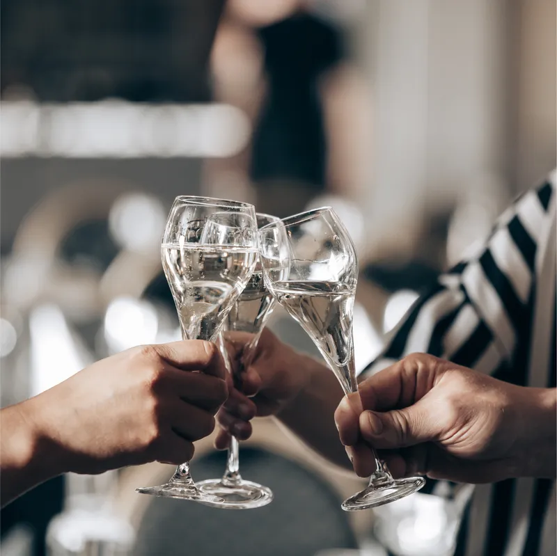 Tre glas mousserande vin som höjs i en skål