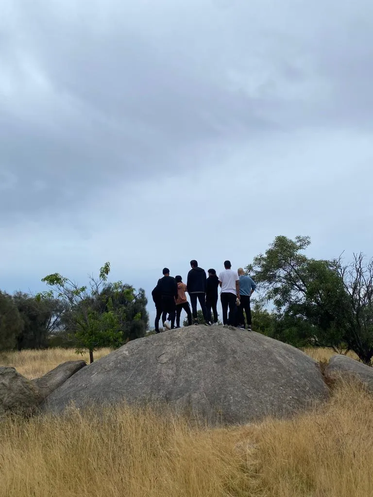 Fajr Club brothers standing together on a big rock in a grassy park