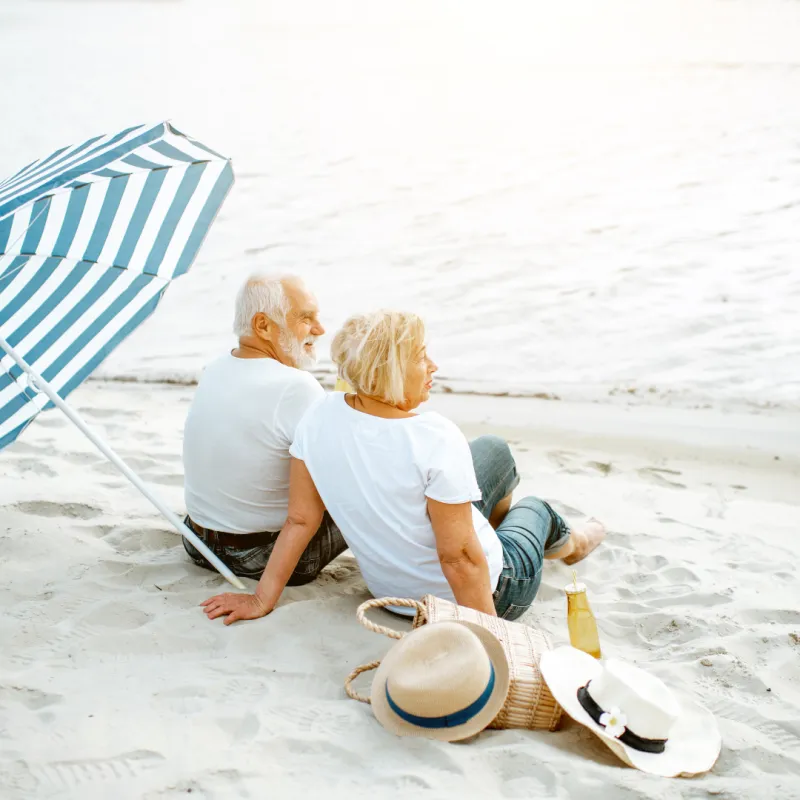 Retired couple relaxing on the beach under an umbrella