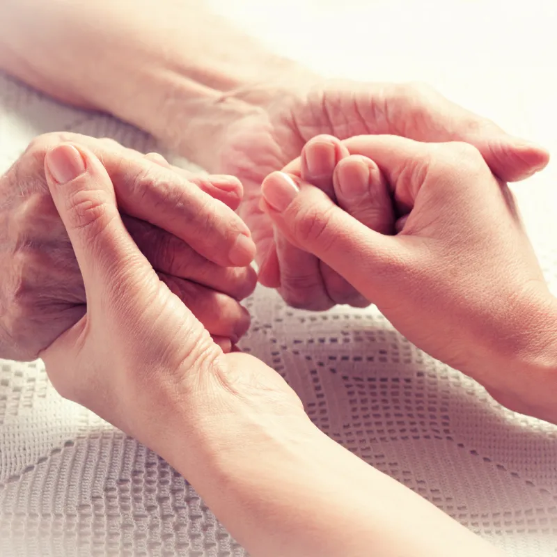 Younger hands holding an older person's hands