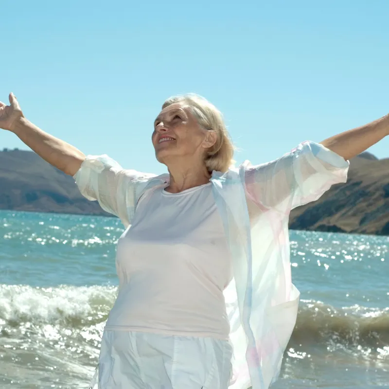 Woman with arms outstretched at the shoreline