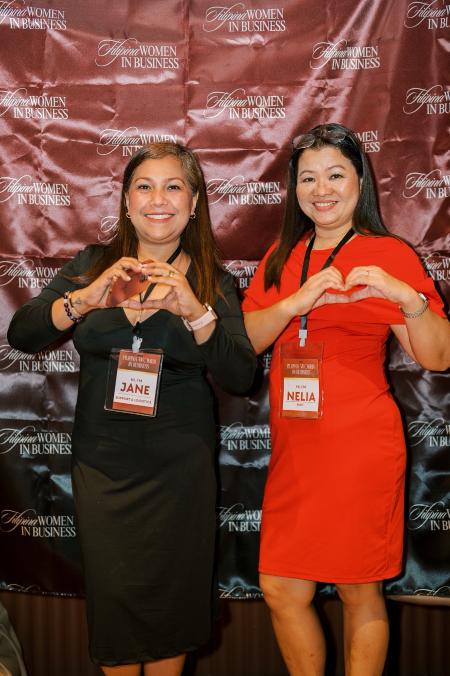 Two FWIB members making heart signs at the photo wall