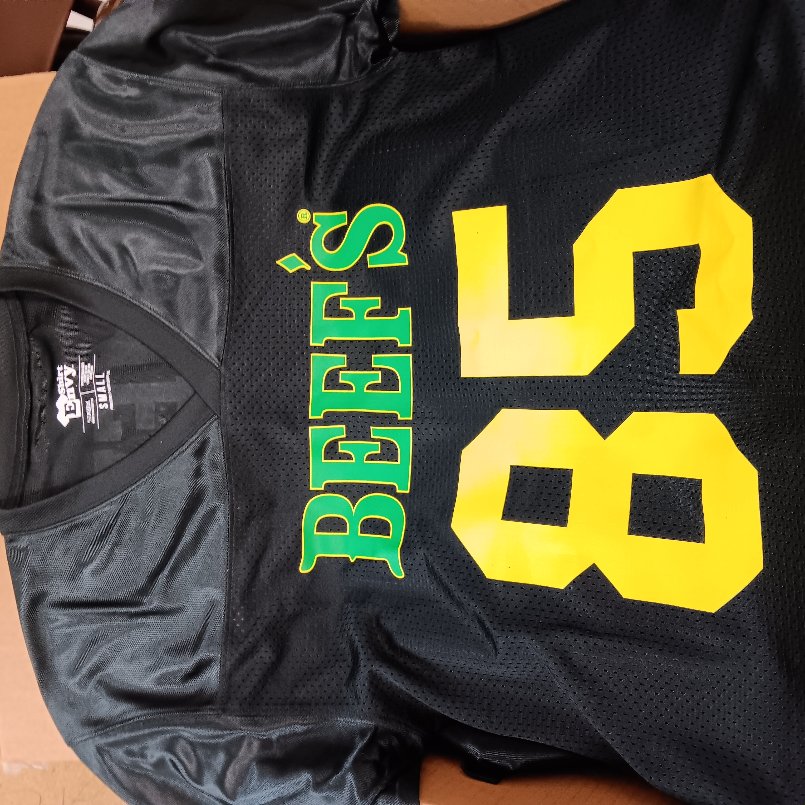 Black team shirt with green lettering and a yellow number