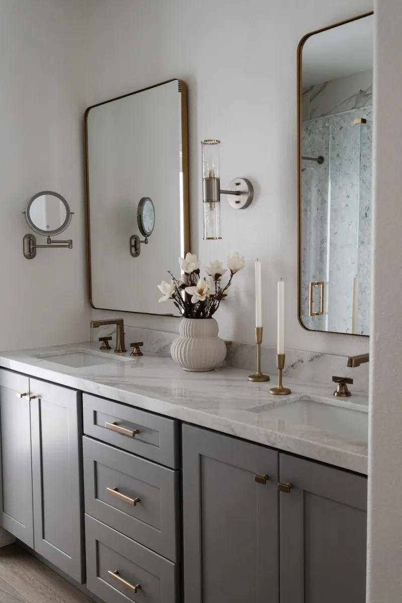 Charcoal vanity with brass fixtures and a backlit mirror