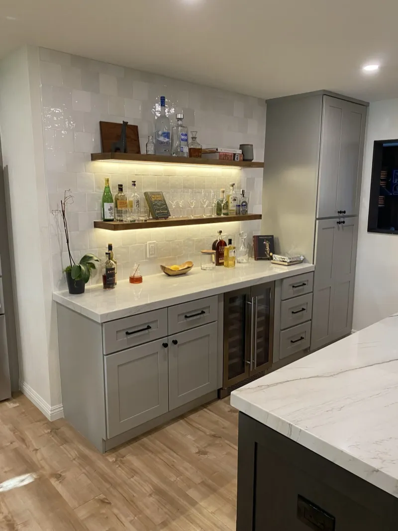 Gray bar cabinets with lit floating shelves and a wine fridge
