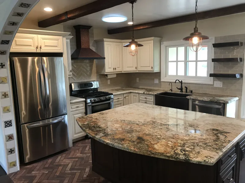 Kitchen with a granite-topped island, cream cabinets and wood ceiling beams