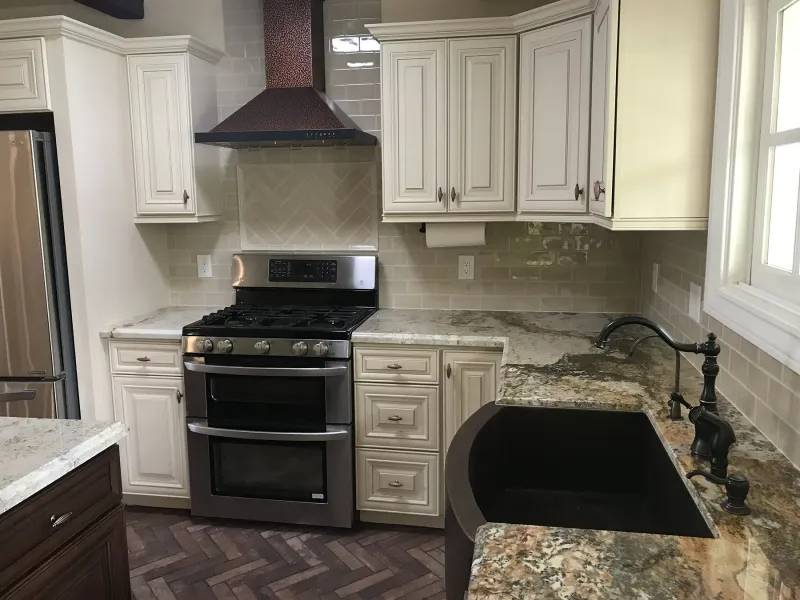 Cream raised-panel cabinets around a range with a copper hood