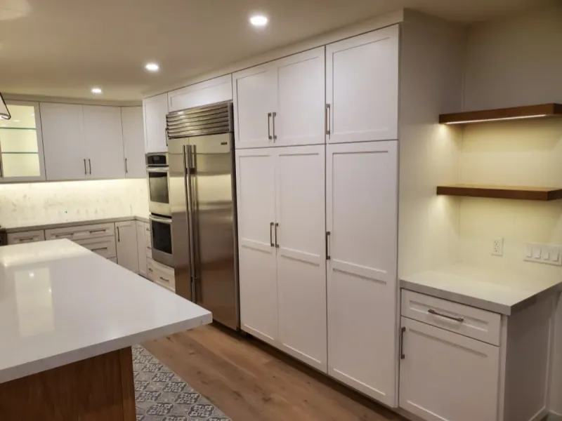 Tall white pantry cabinets beside the fridge, with oak shelves