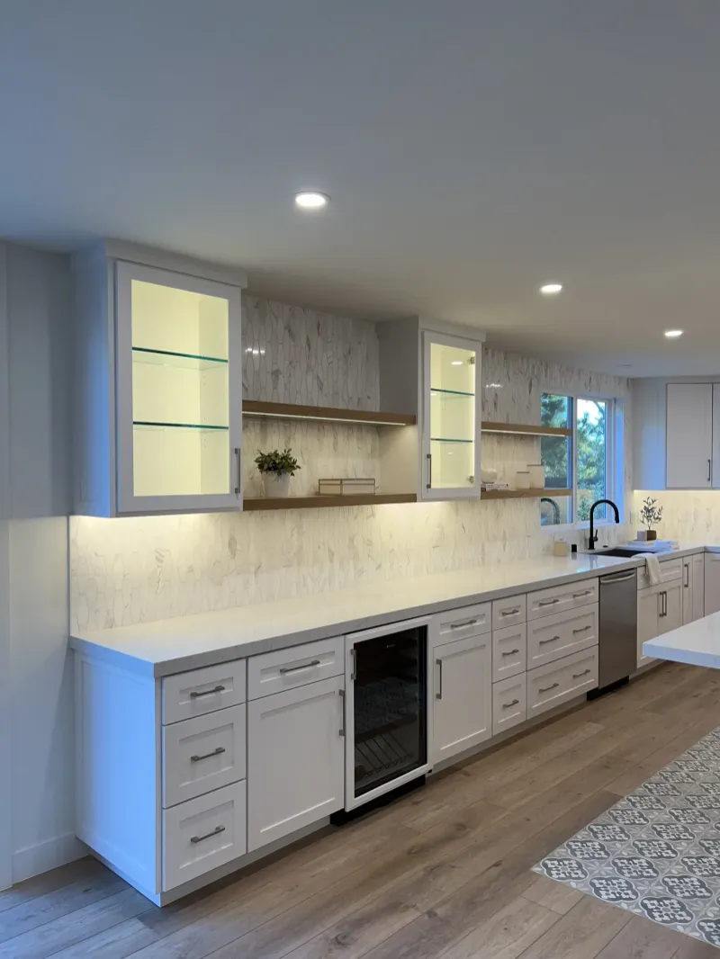 White cabinet run with lit glass upper cabinets and a wine fridge