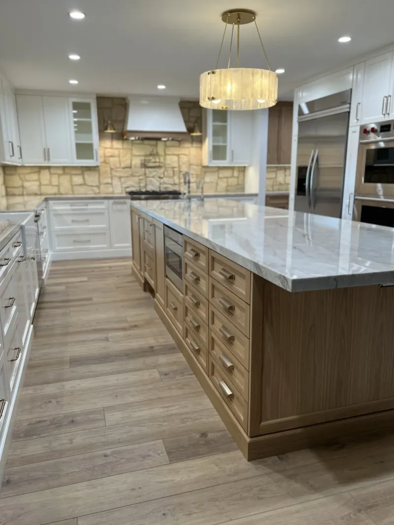 Oak island with a bank of drawers beside white perimeter cabinets