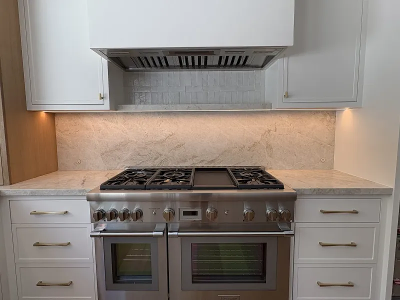 White cabinets around a professional range and hood