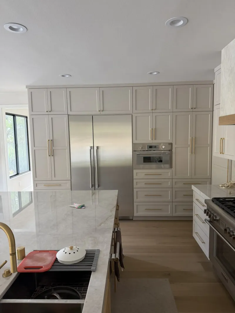 White tall cabinets around a built-in refrigerator, island sink in front