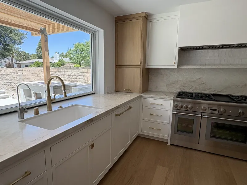 White kitchen with a sink under a window and a pro range