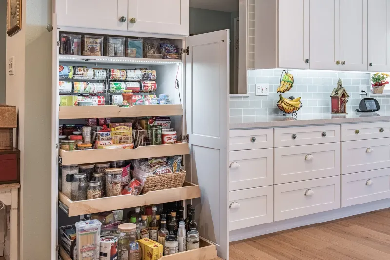 Tall white pantry cabinet with open wooden pull-out drawers
