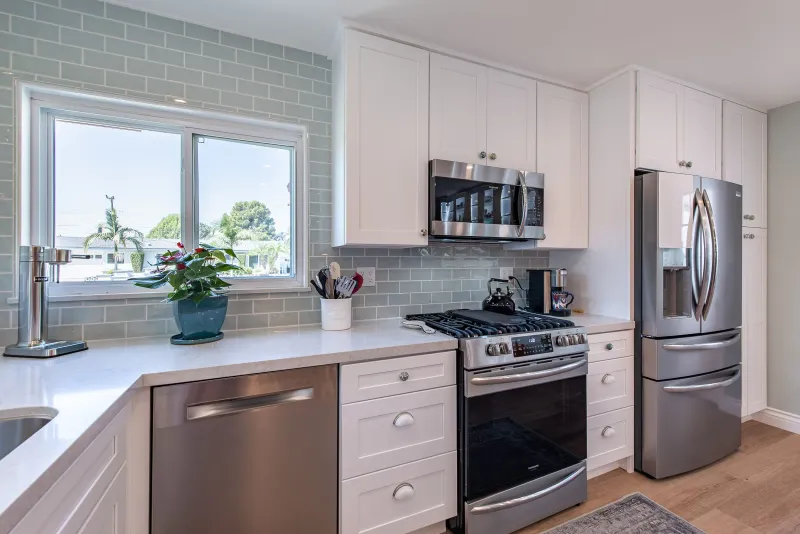 White shaker sink wall under a window with stainless appliances