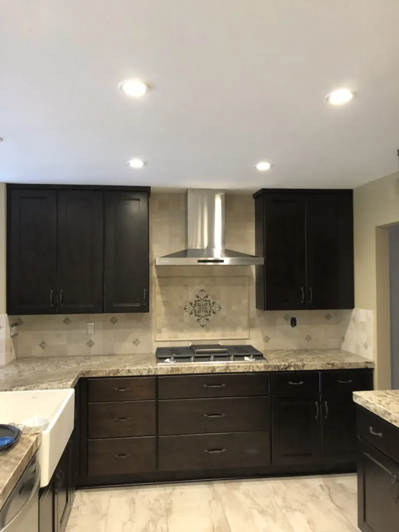 Espresso cabinets around a stainless range and chimney hood