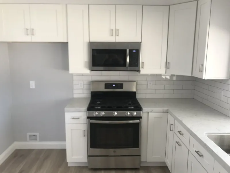 White shaker kitchen with subway tile and a stainless range