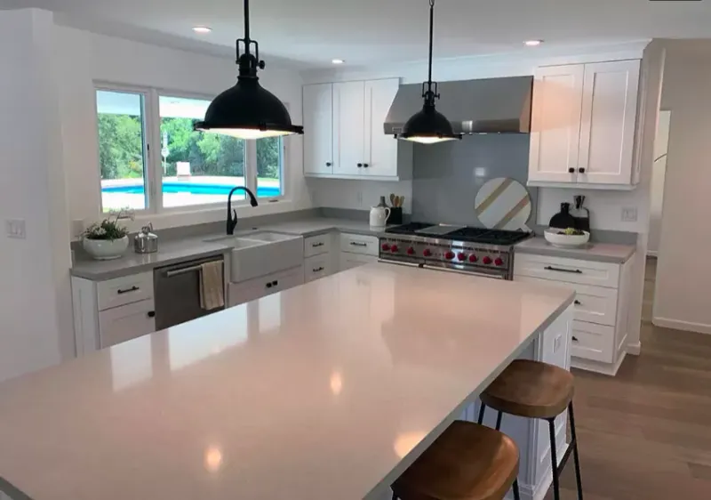 White kitchen island under black pendant lights