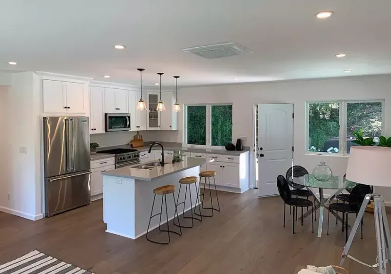 White kitchen with an island, open to the dining area