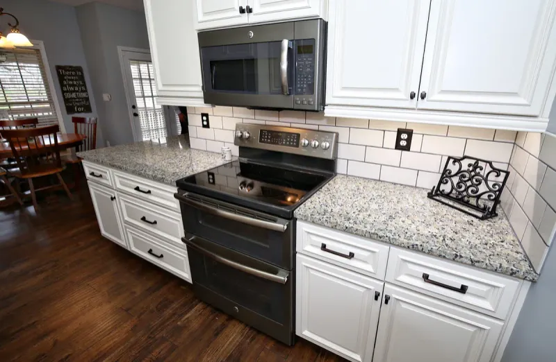 White kitchen cabinets with granite counters and a stainless range