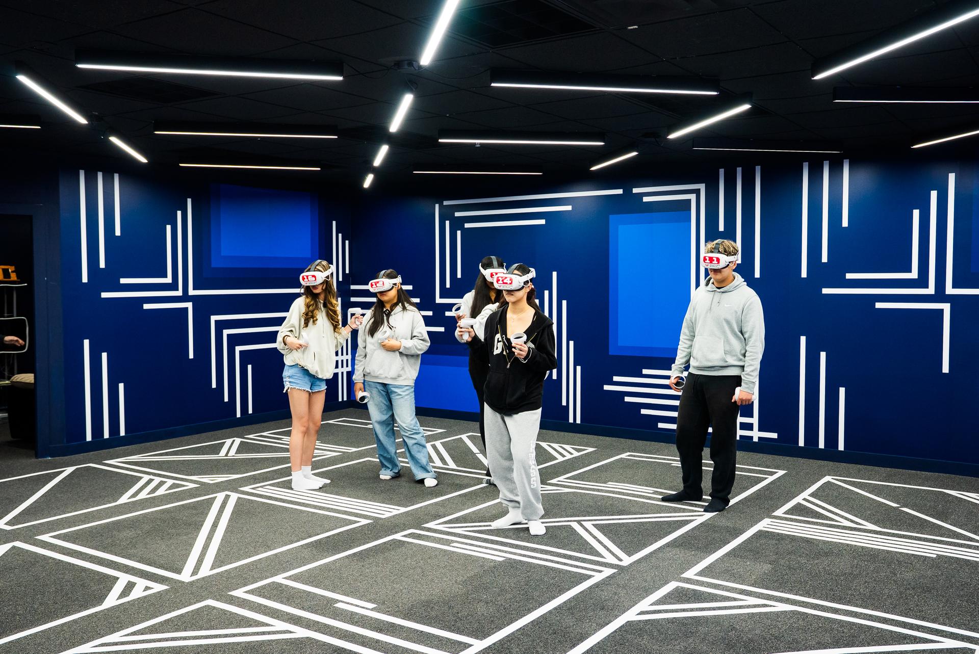 Students in headsets in the blue arena under the light strips