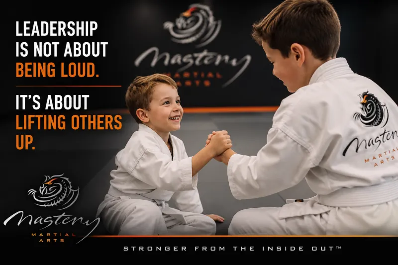 Quiet child in a Mastery Martial Arts uniform helping another student during class. Quiet child in a Mastery Martial Arts uniform helping another student during class.
