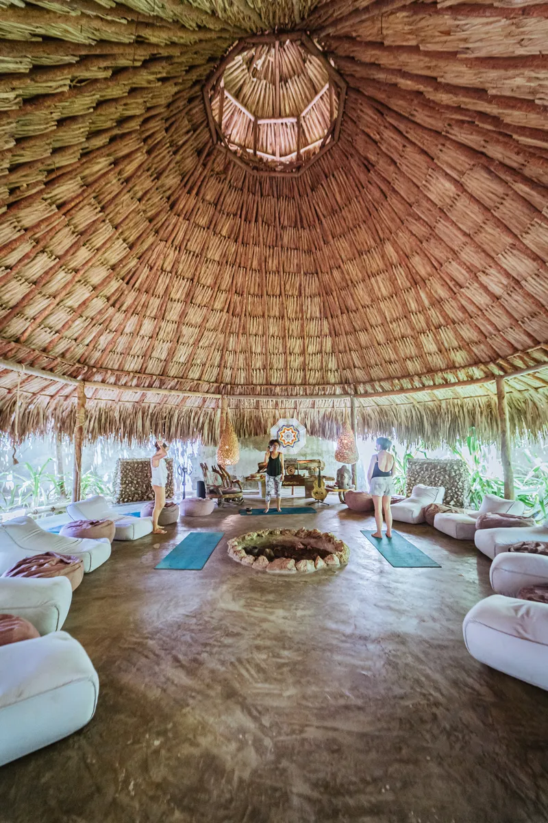 Espacio circular techado de palma con cojines blancos