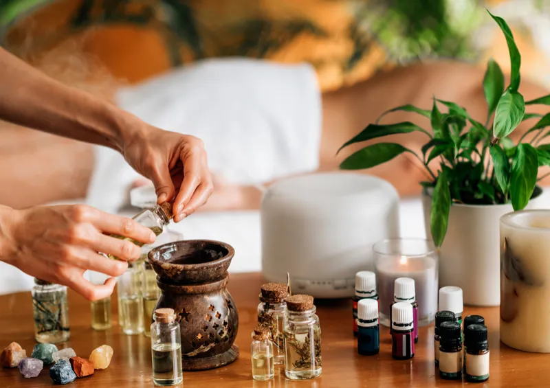 Manos preparando aceites y aromas sobre una mesa con plantas