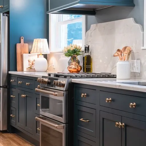 Navy painted kitchen cabinets with brass hardware and a marble slab backsplash
