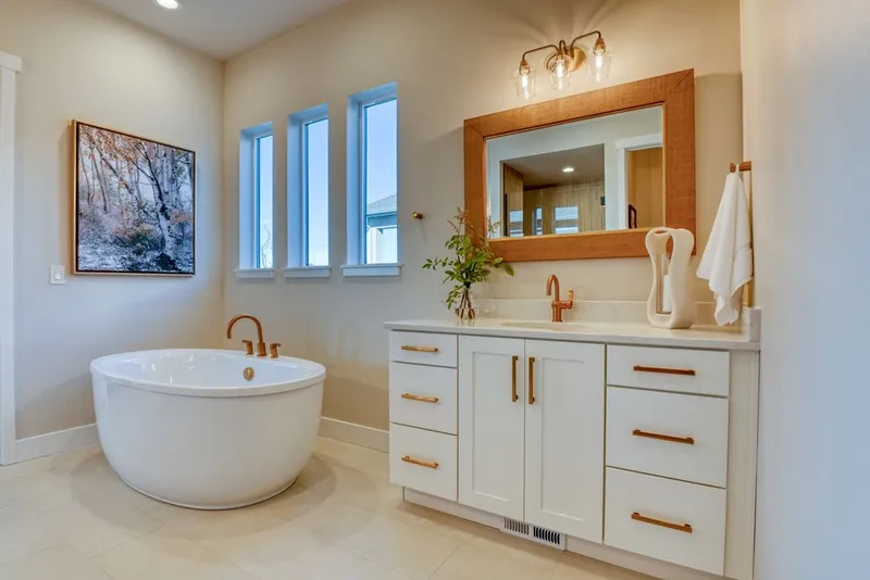 White shaker bathroom vanity with rose-gold hardware beside a freestanding tub