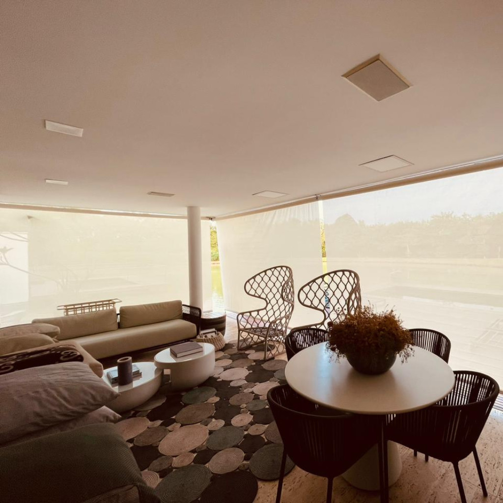 Sala de estar protegida com toldo cortina em casa de condomínio à beira do lago