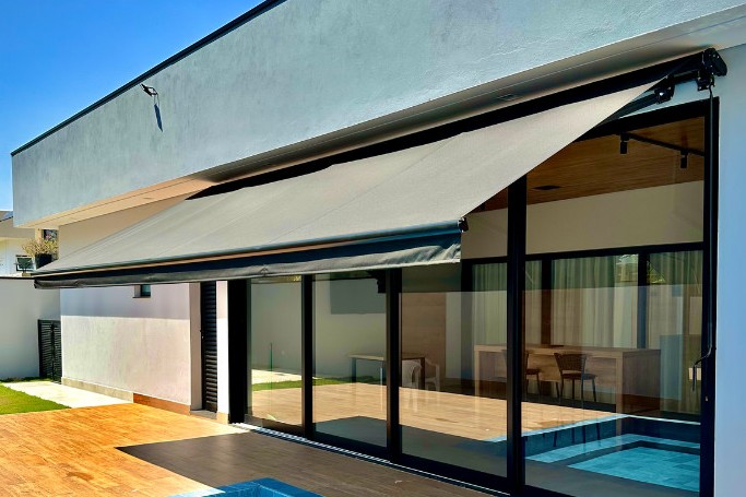 Cobertura retrátil (toldo retrátil) em alumínio sobre deck e piscina de casa moderna