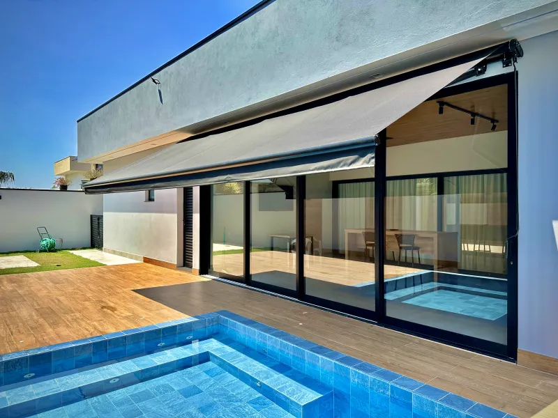 Toldo articulado retrátil estendido sobre piscina em residência de alto padrão