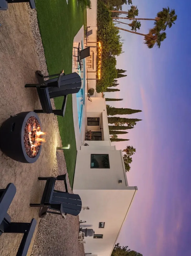 Round fire pit with chairs at dusk beside pool and palms — fire feature Phoenix AZ