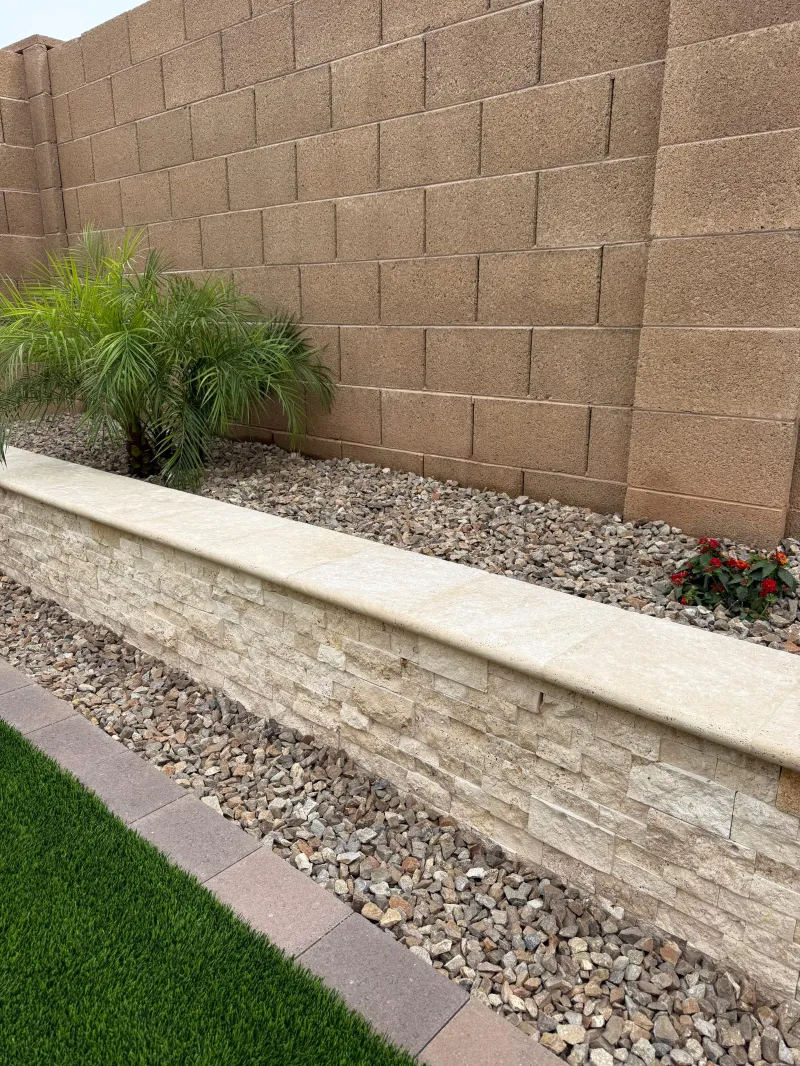 Stone retaining wall with artificial turf and river rock — hardscaping Phoenix AZ