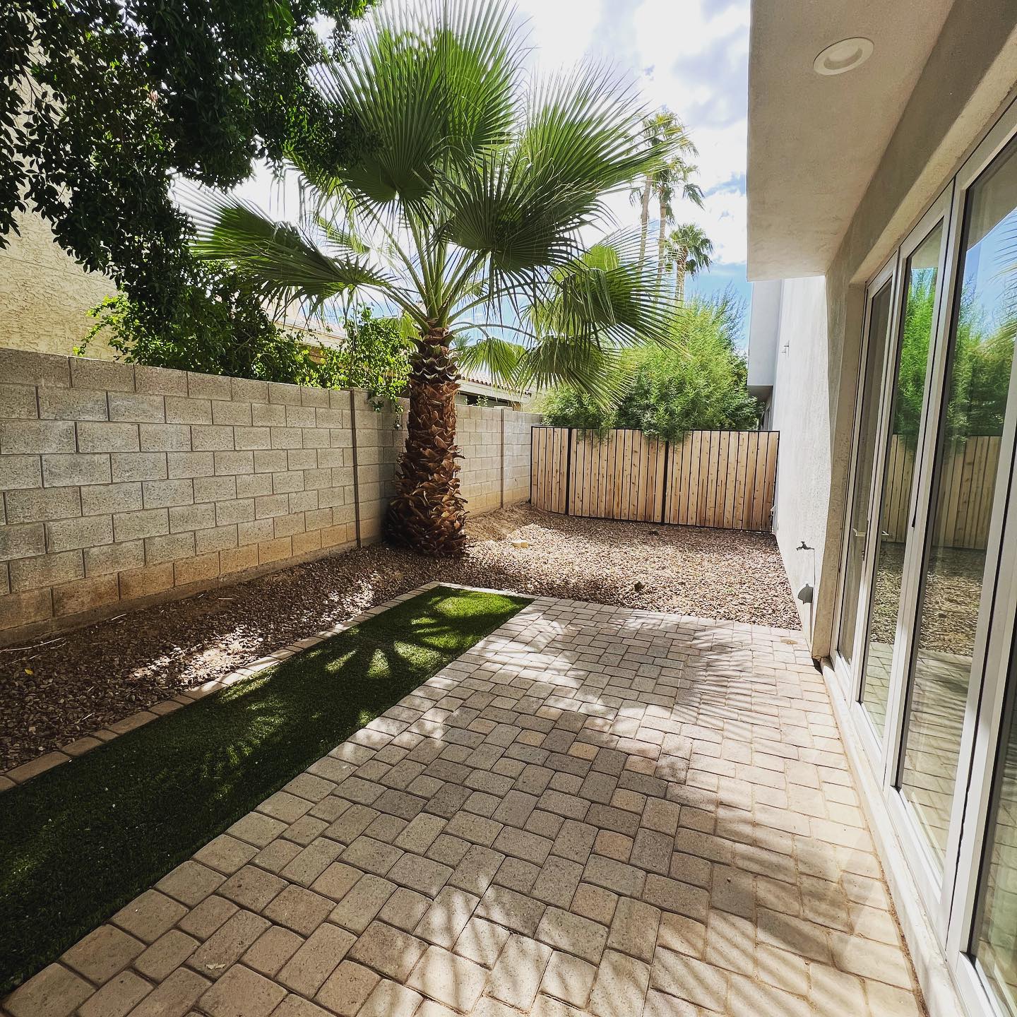 Finished side yard walkway: paver patio with turf strip, palm tree, and block wall, concrete and paving Phoenix AZ