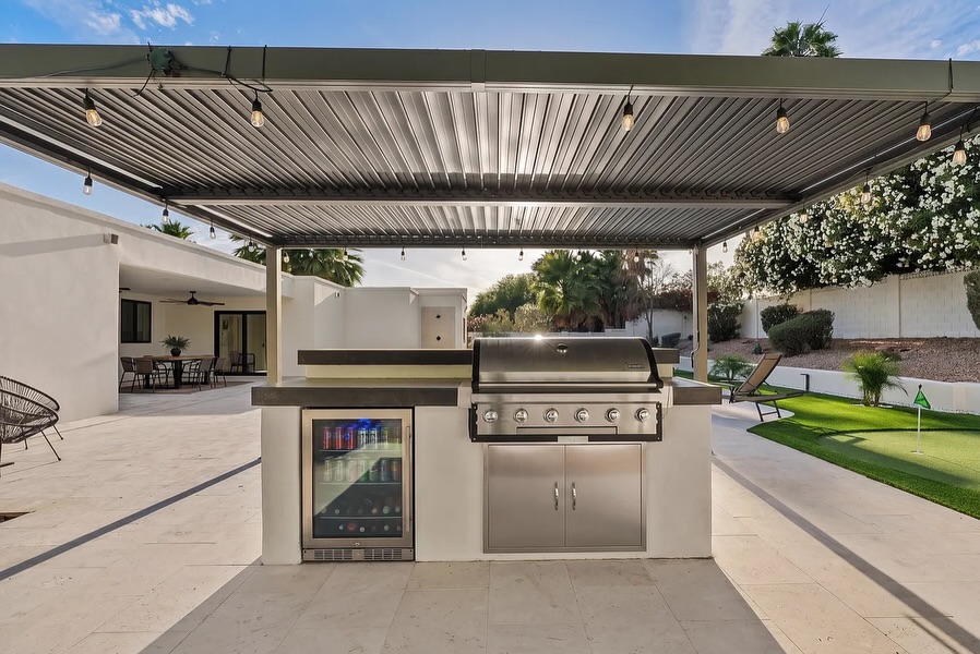 Covered patio with metal pergola, Edison string lights, and travertine deck, outdoor living Phoenix AZ