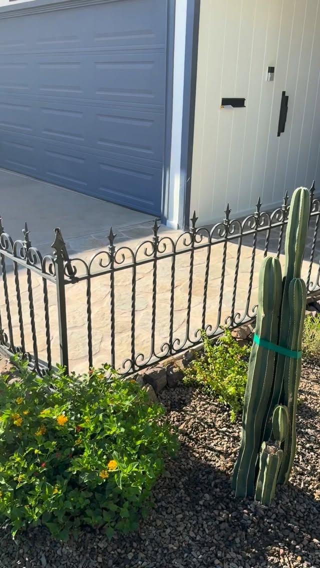 Desert planting bed with scroll fence, lantana, staked column cactus, and flagstone