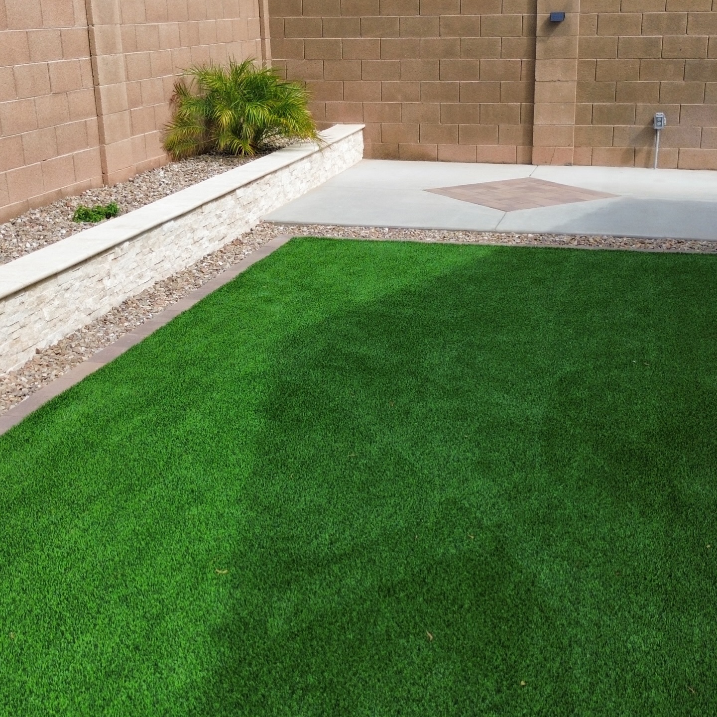 Backyard turf with stacked-stone planter wall and paver accent patio