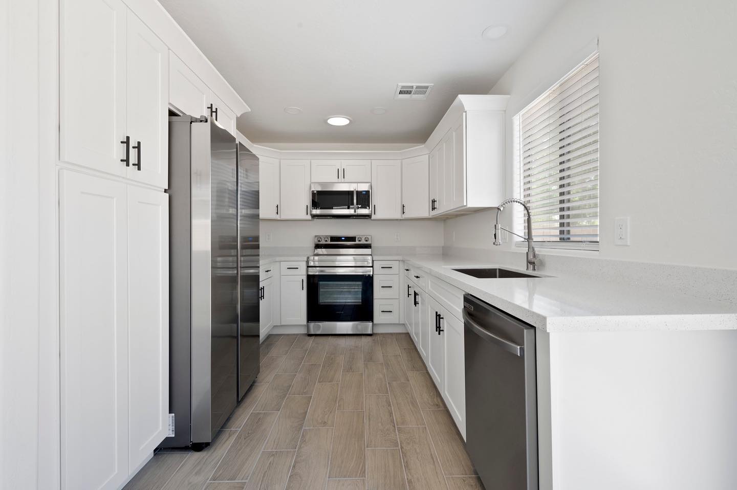 Remodeled white kitchen with stainless appliances and quartz counters
